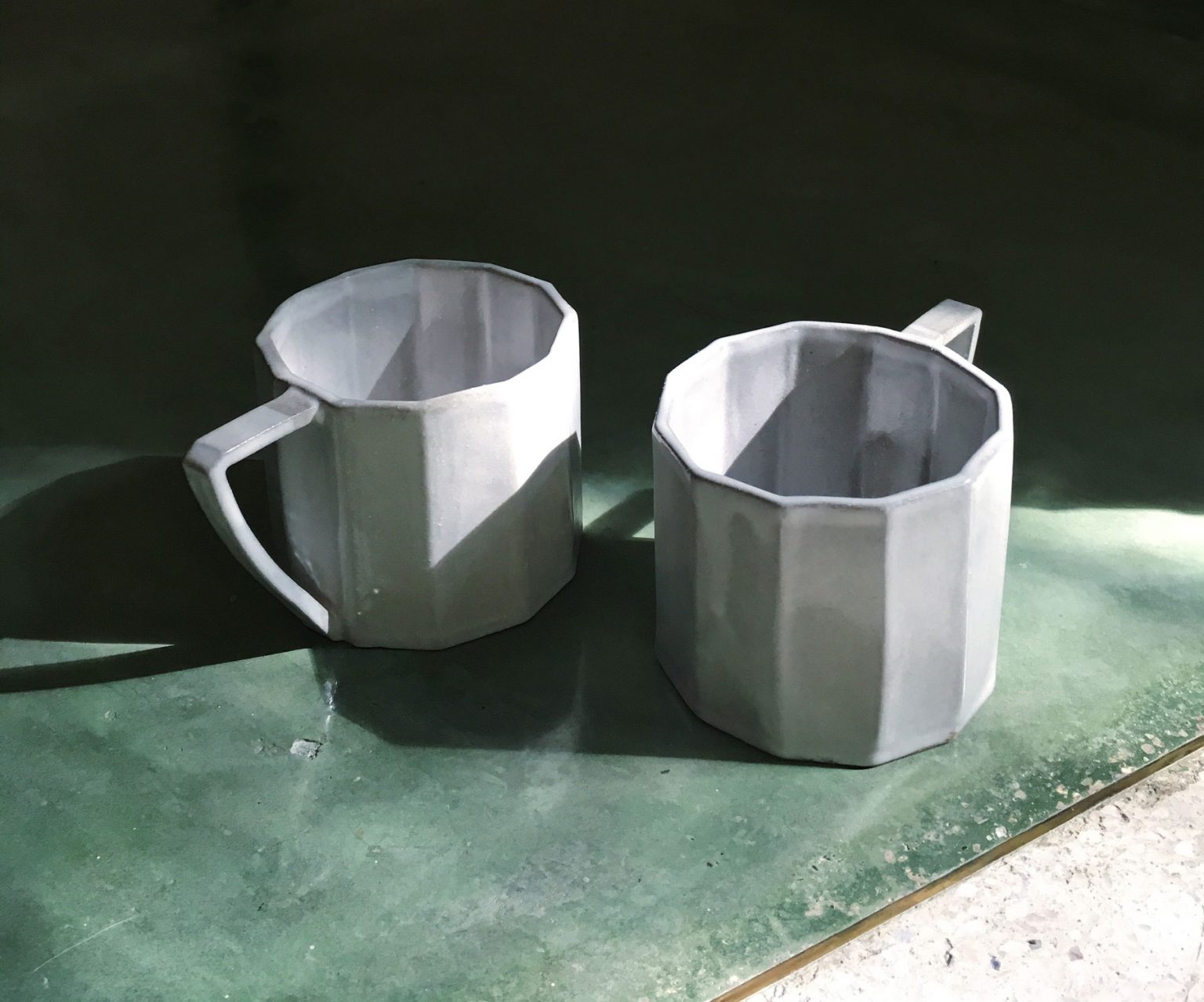 Two white ceramic coffee cups resting on a table.