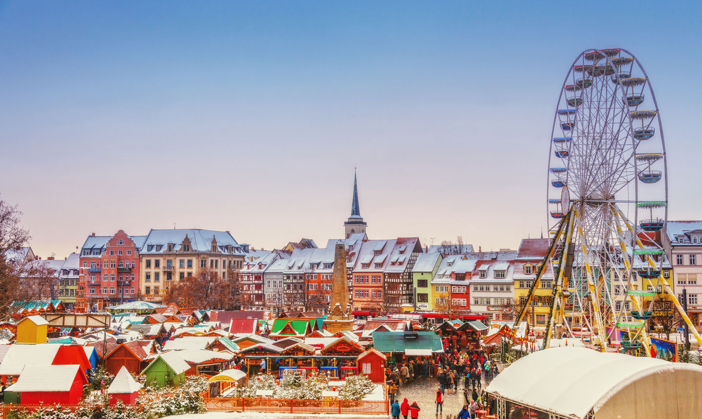 A crowded Christmas market with a ferris wheel.
