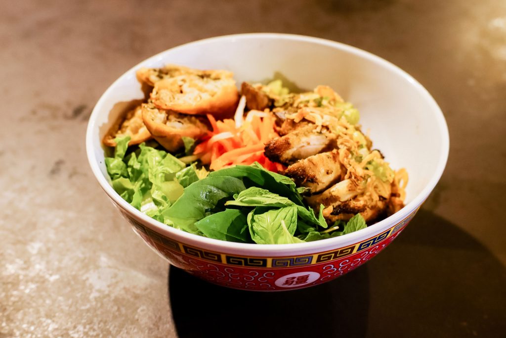 A bowl of Viatnamese noodles topped with grilled chicken.