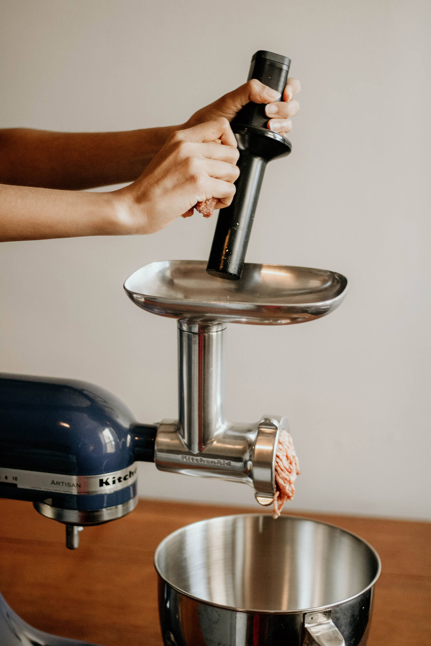 A KitchenAid® stand mixer with gently grinding meat with a food grinder attachment.