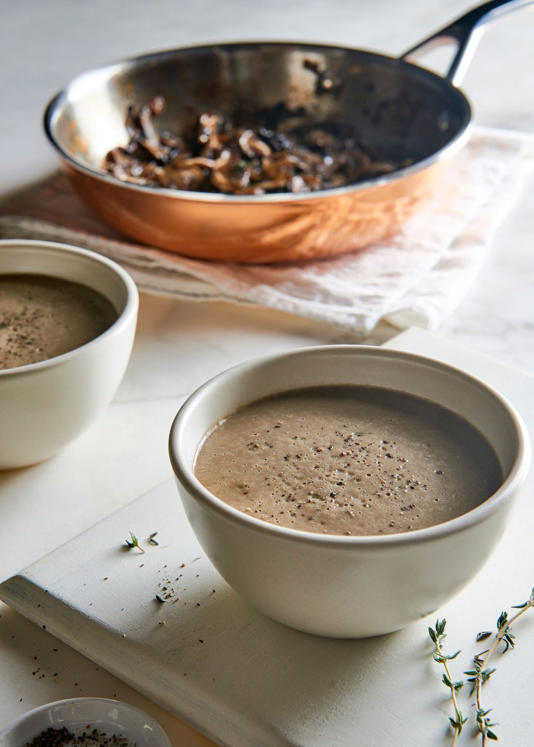 Two white bowls of creamy magic mushroom soup.