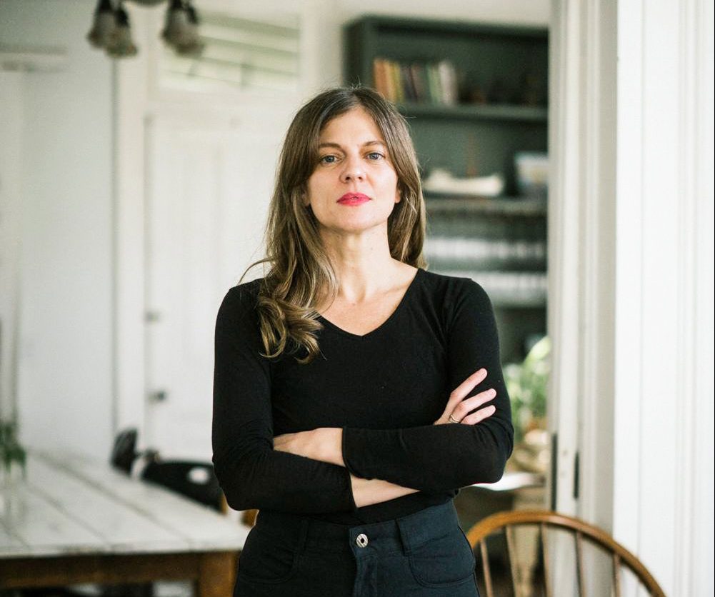 Melissa M. Martin standing with arms crossed behind a stake of white plates.