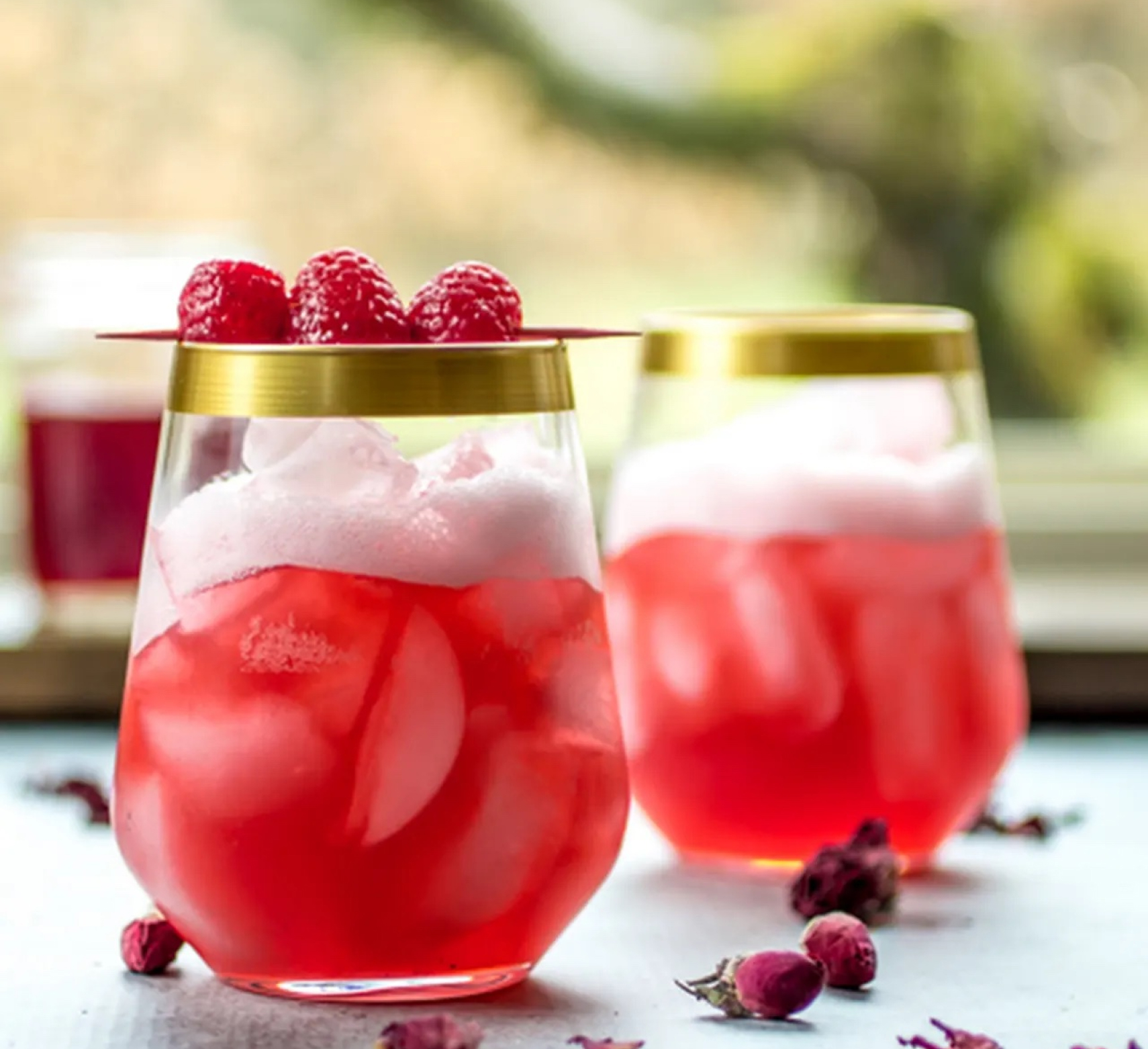 A pair of vibrant pink cocktails in stemless wine glasses.