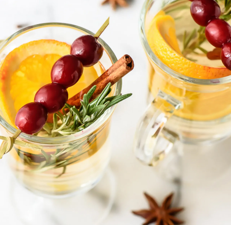A well-garnished cocktail with cinnamon sticks, orange slices and more.