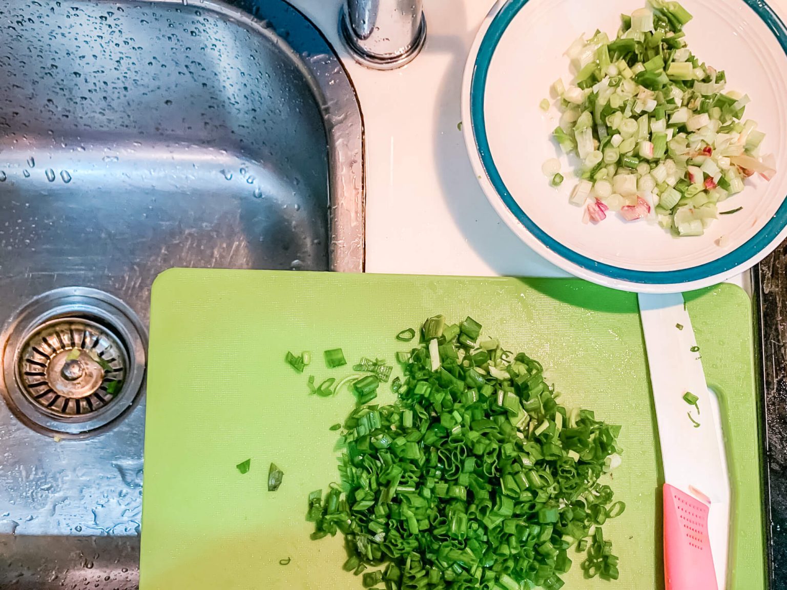 Chopped green onions on a cutting board and in a bowl.