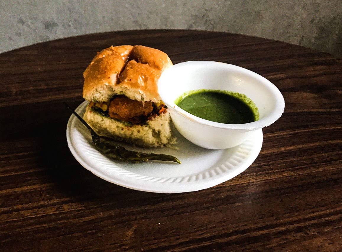 Vada pav, a spiced potato slider, resting on a plate.