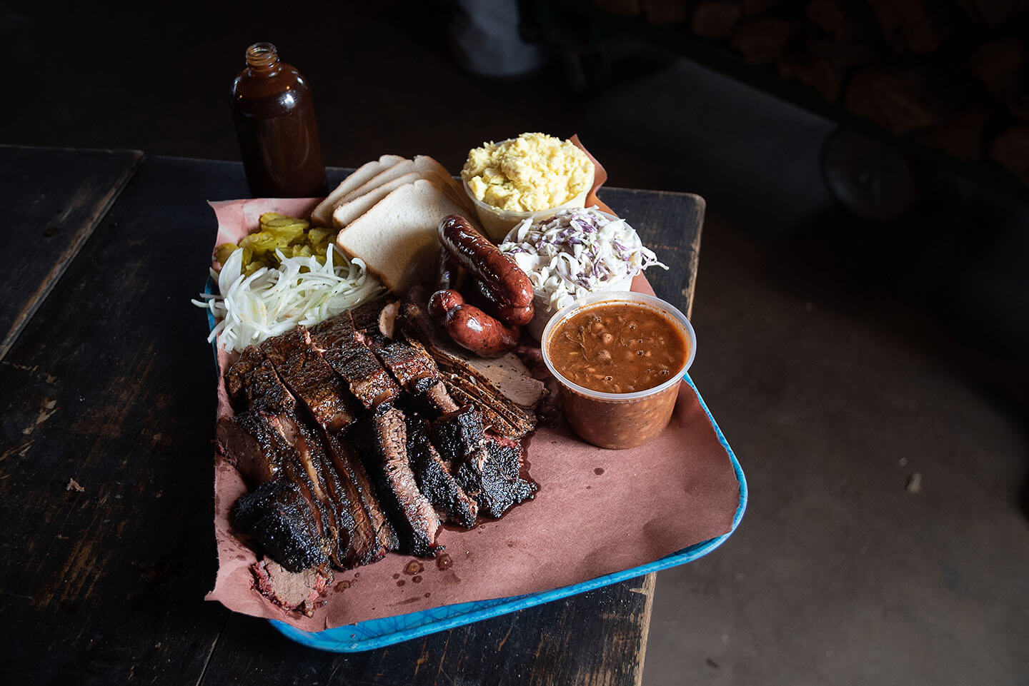 A tray of ribs ready to be served with baked beans, coleslaw and other fixings.