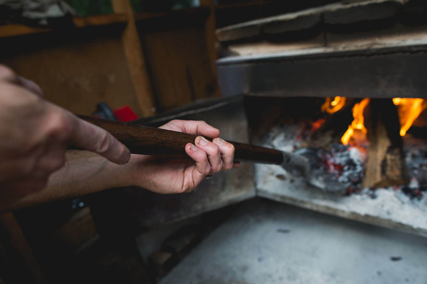 A person shoveling charcoal around in a charcoal-buring stove.