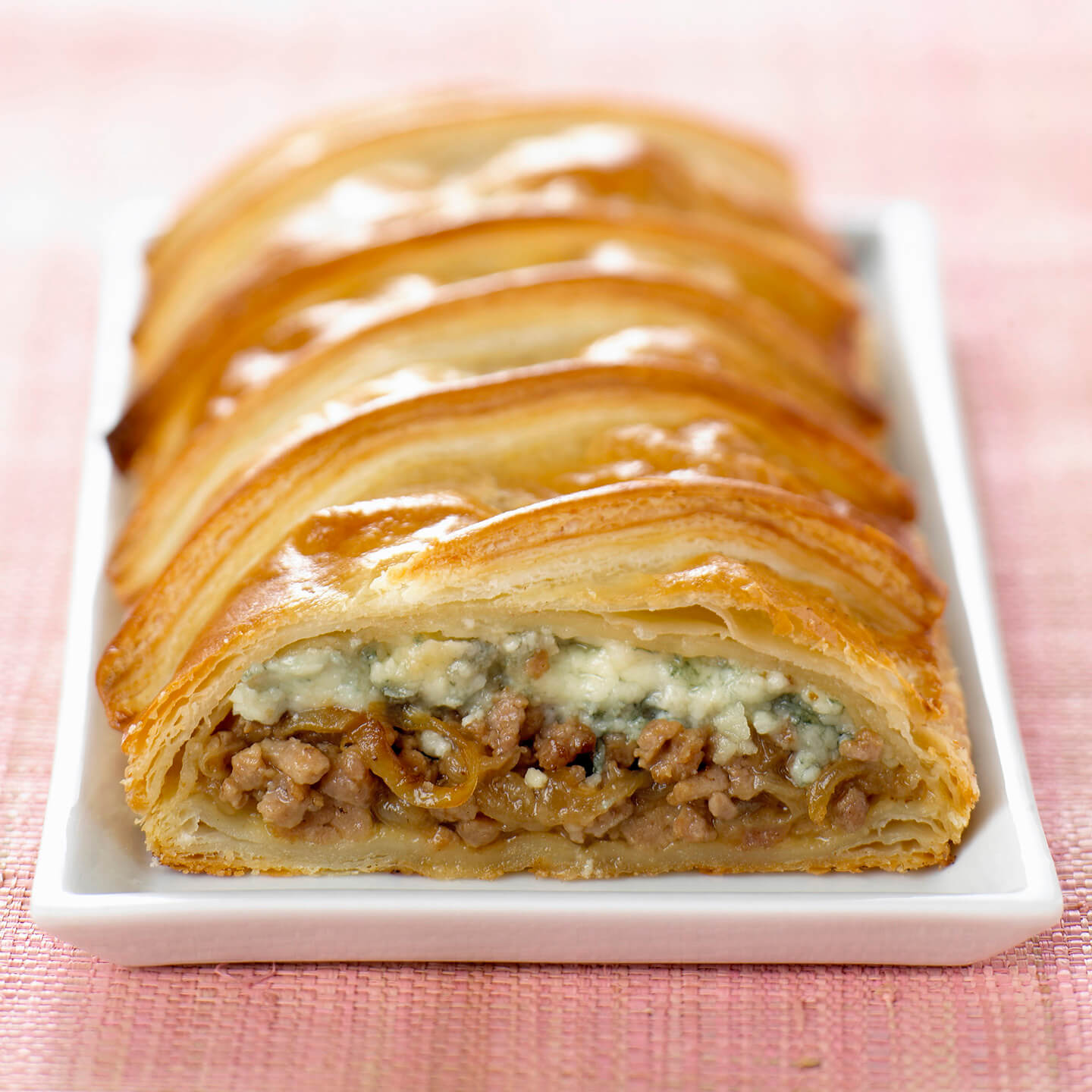 A white dish holding a freshly baked, crispy kolache.