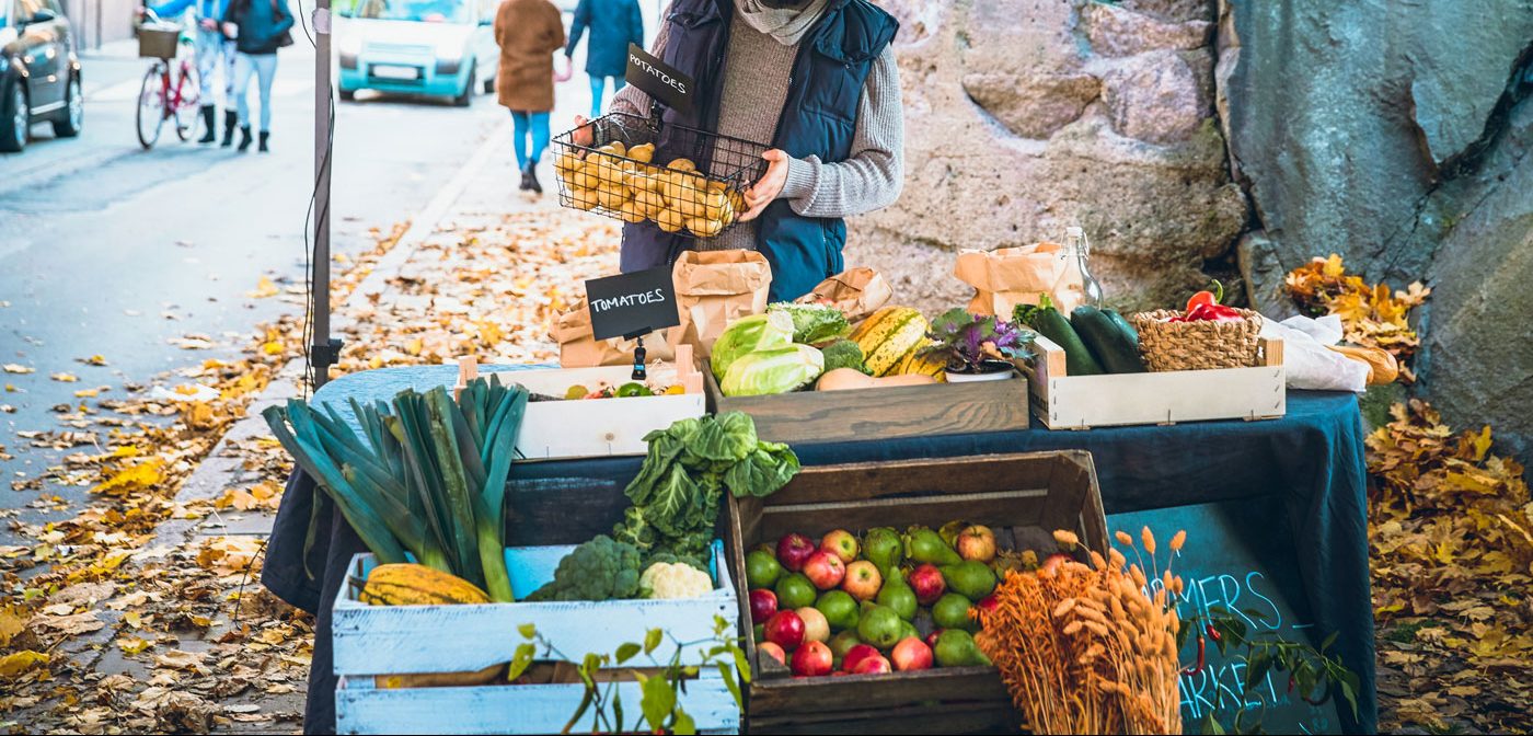 A person arranging a vegetable stand filled with organic vegetables.