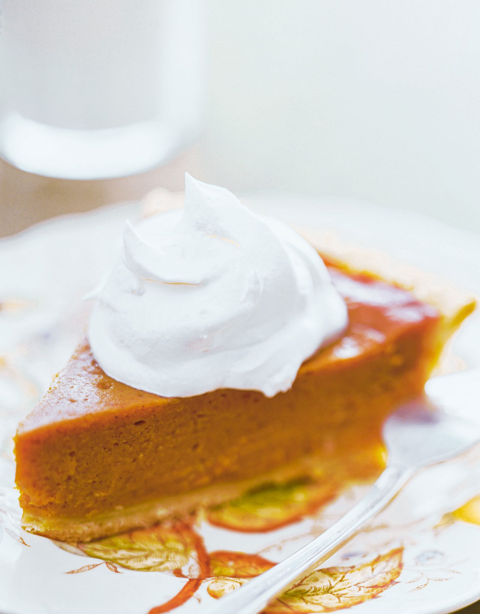A clean slice of sweet potato pie with a huge dollop of whip chream.