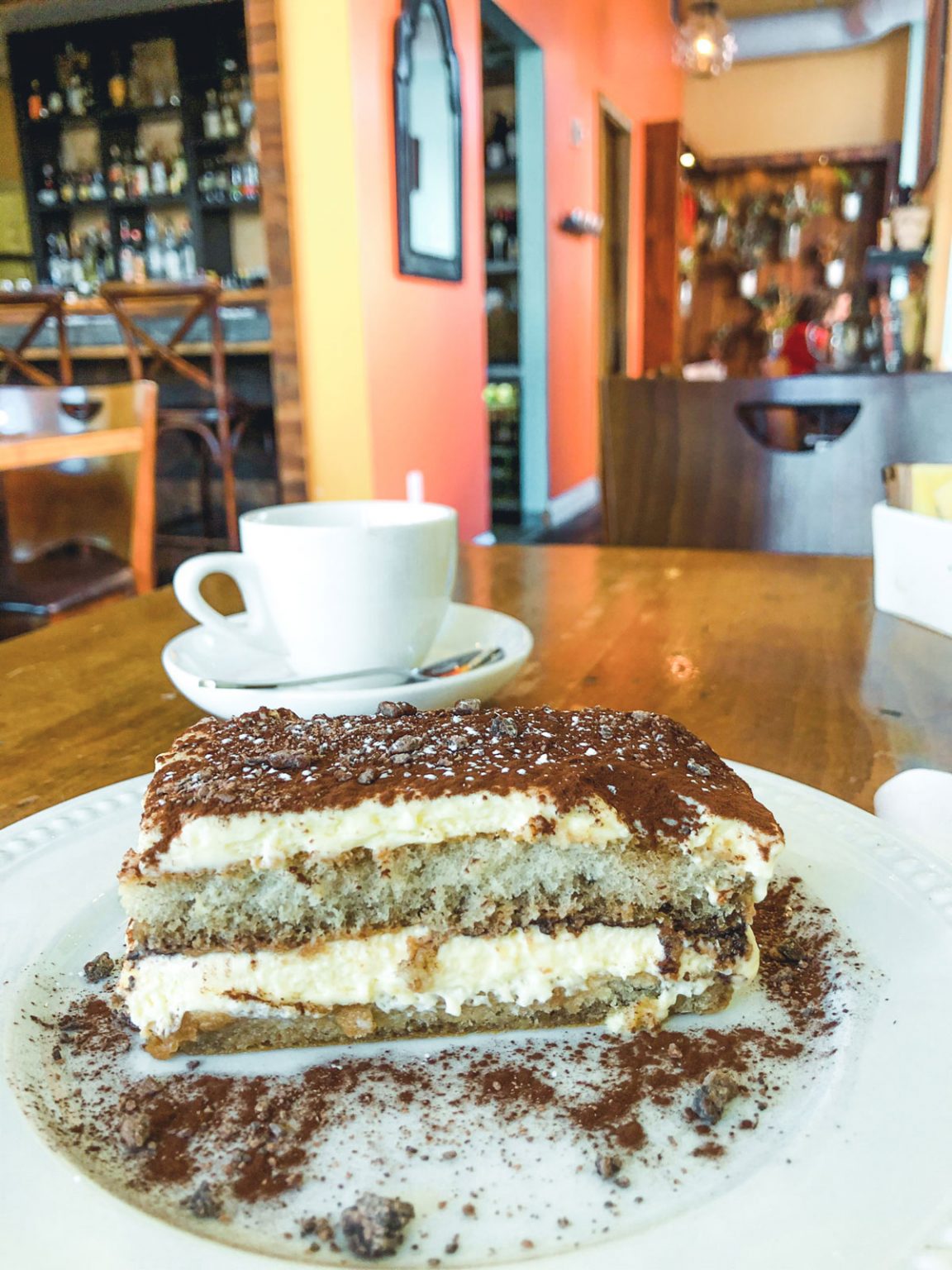 A slice of tiramisu resting on a white dish.