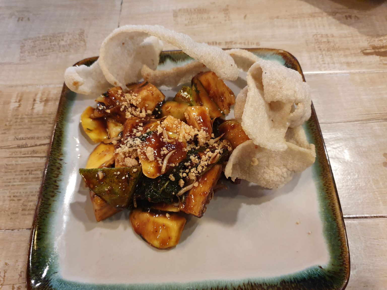 A square, ornate dish filled with vegetable rojak.