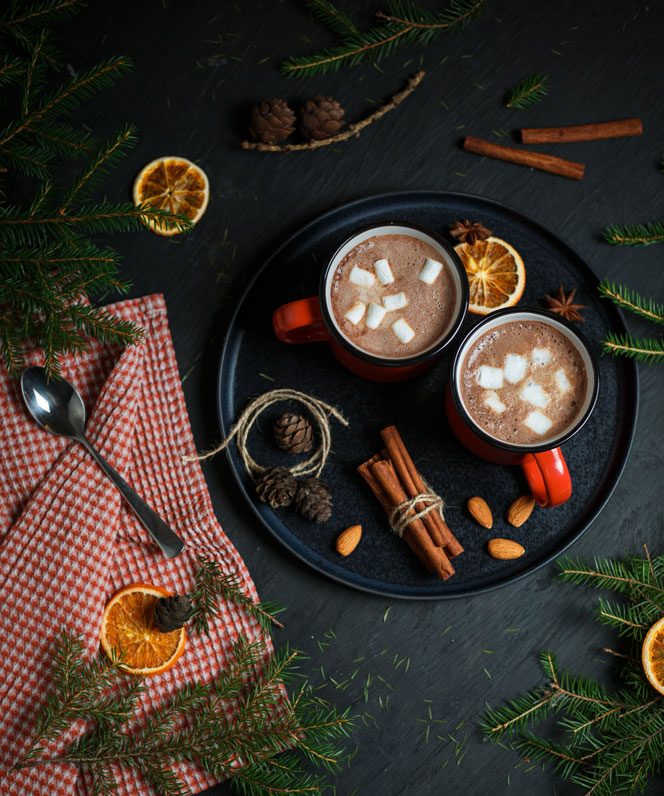 Two mugs of hot chocolate resting on a tray.