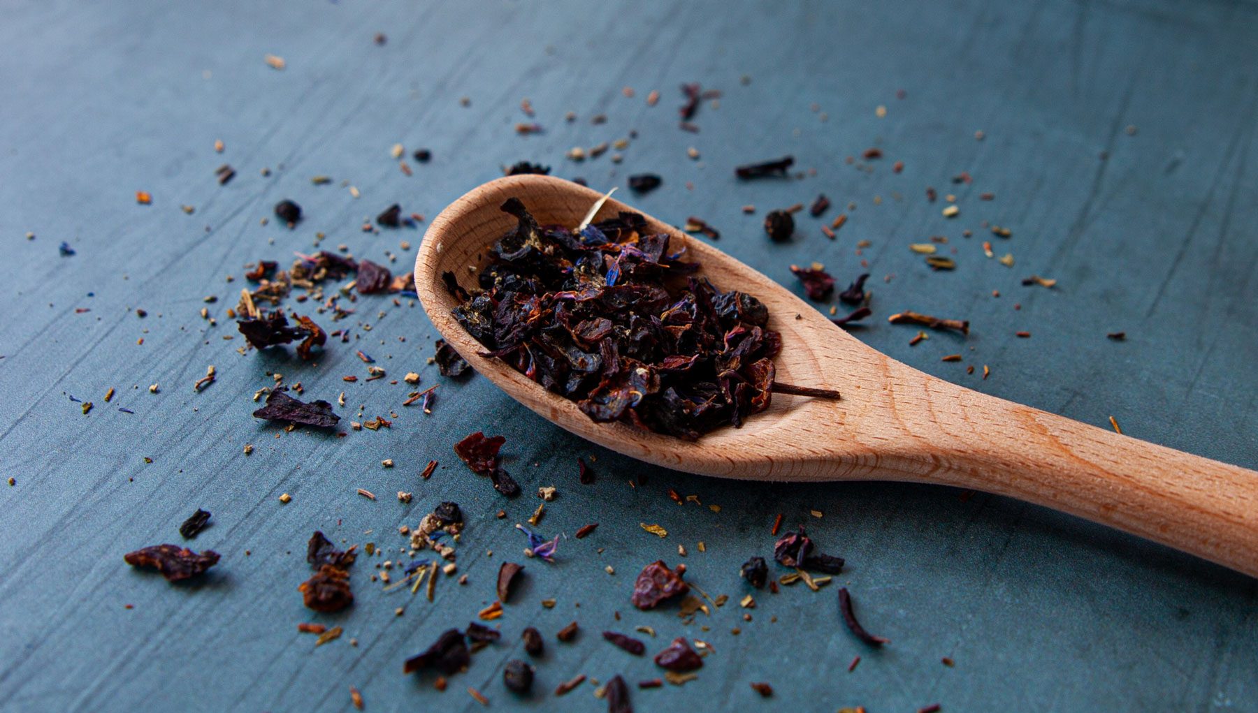 A wooden spoon filled with dried black tea leaves.