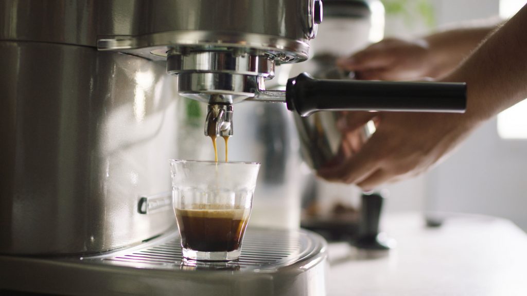 A person making espresso with a KitchenAid® Pro Line® Series Espresso Maker.