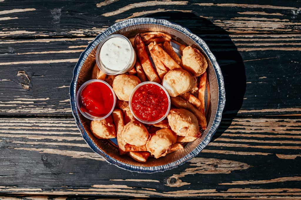 A dish filled with fried clam strips and various sauces.