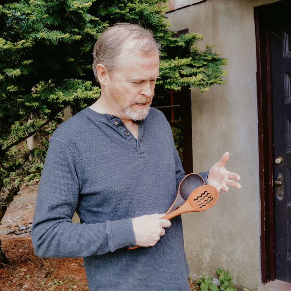 Jonathan Simons holding two wooden utensils.