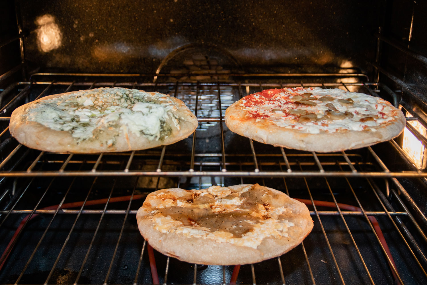 Three pizzas baking in a large oven.