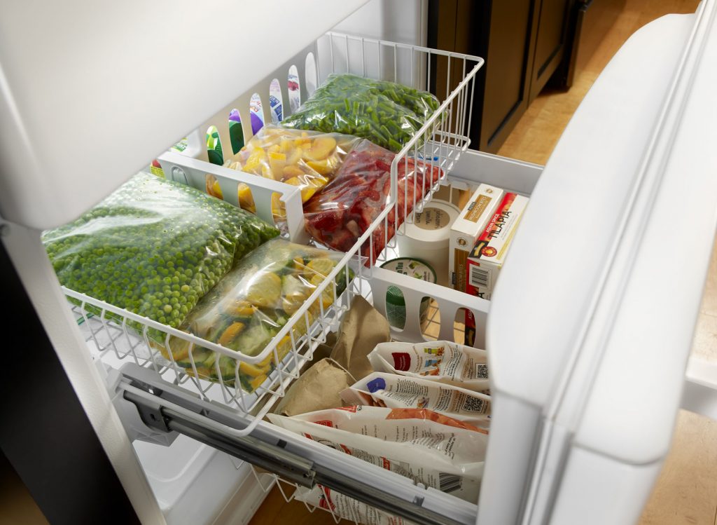 A freezer filled with separate plastic bags of frozen fruits and vegetables.