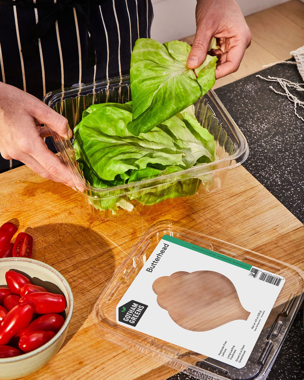 A person selecting a leafy green from a container.