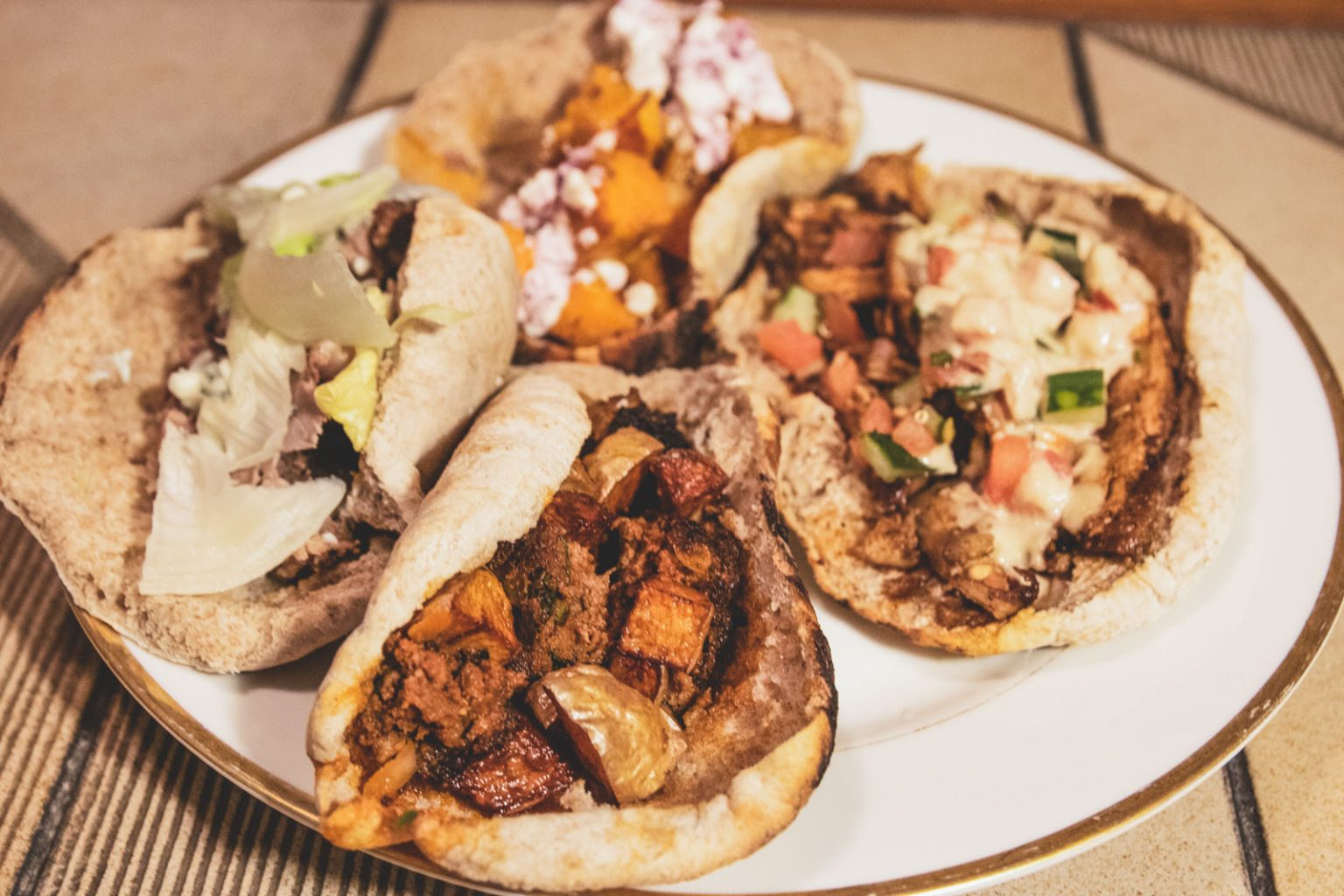 A plate filled up with a variety of different shwarma wraps.