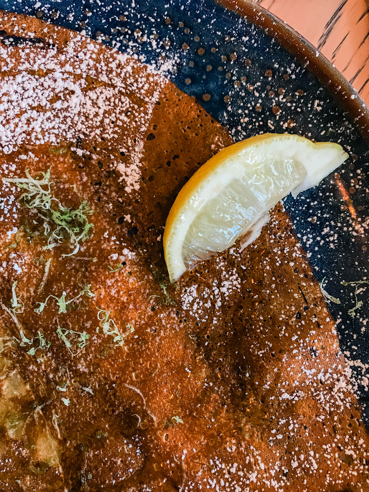 A crispy crepe with a slice of lemon.