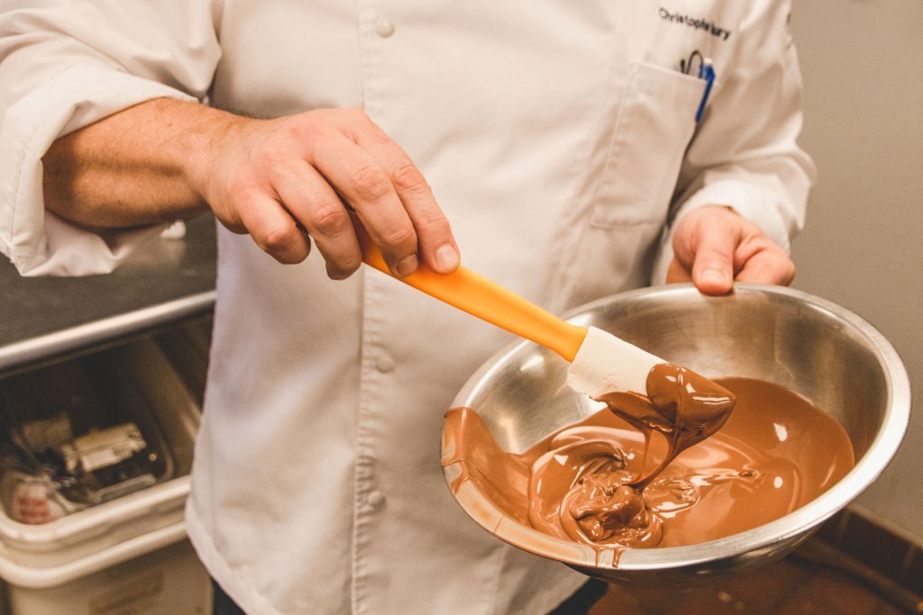 Chef Christophe Toury mixing a bowl of chocolate with a spatula.