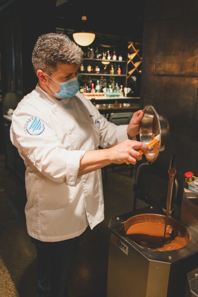 Chef Christophe Toury gently scraping a bowl filled with chocolate.