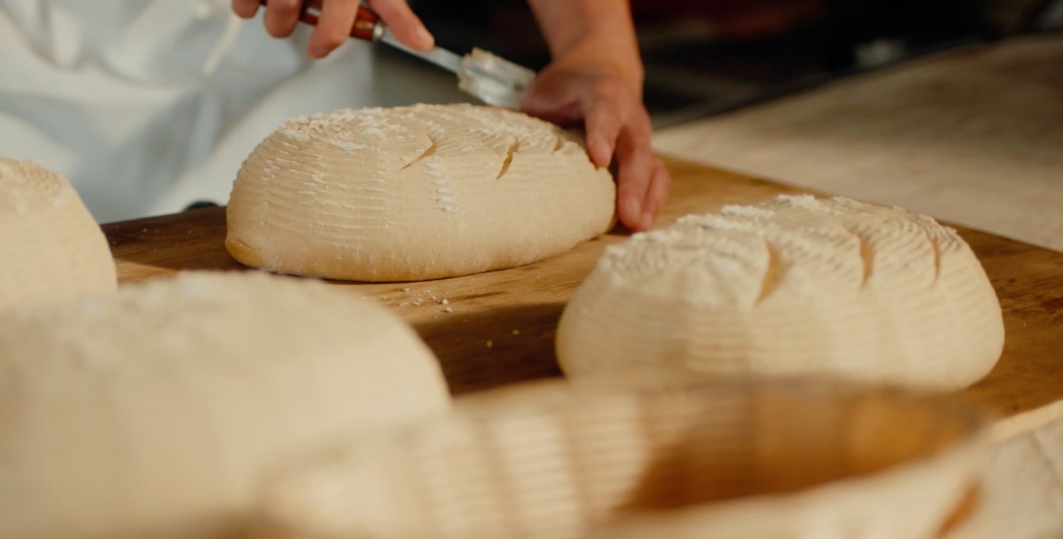 A person slicing into dough.