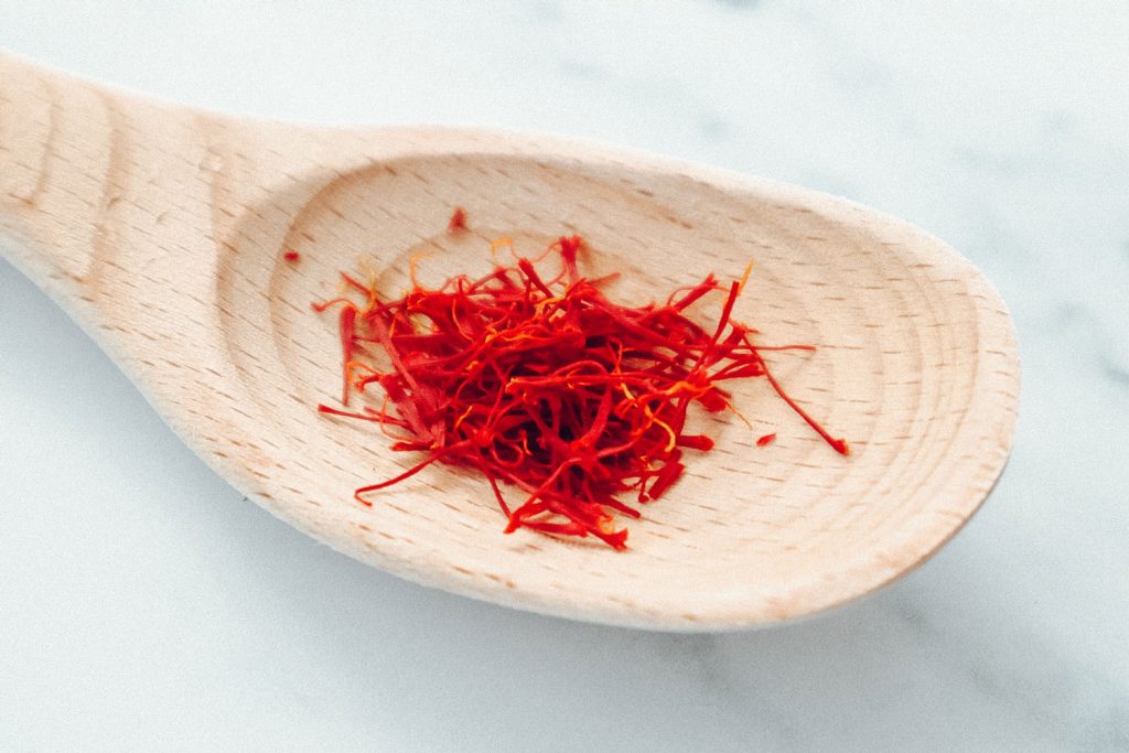 A large wooden spoon holding saffron.