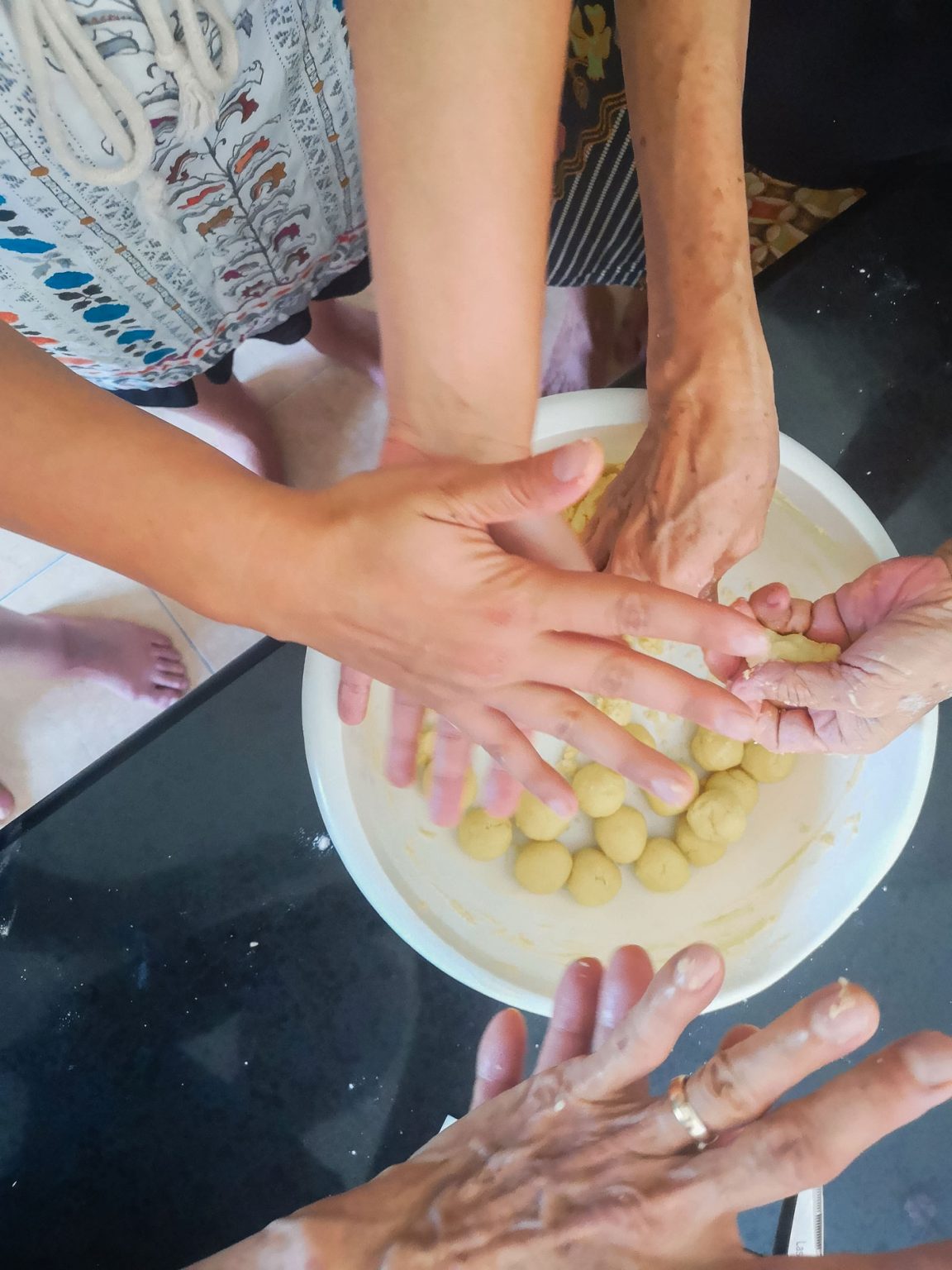 Gentle hands forming small balls of dough.
