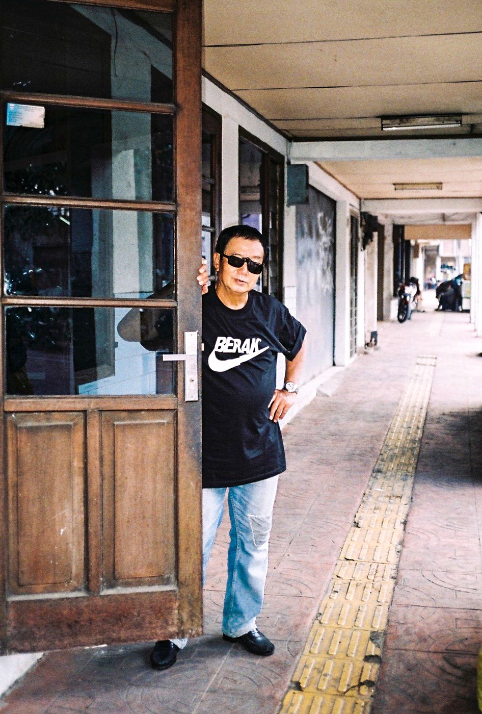 Paulus Supomo in black sunglasses holding a door open.