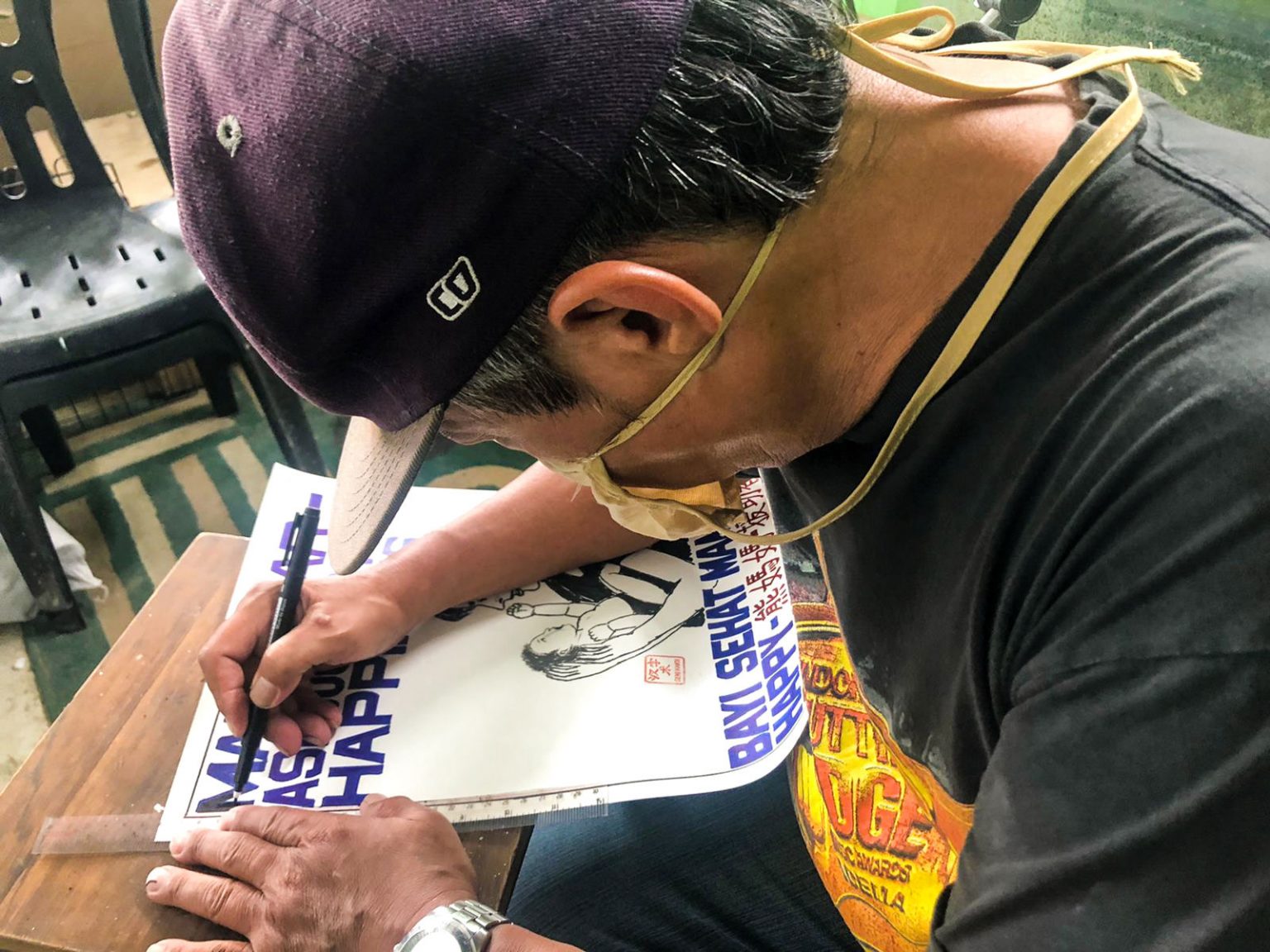 Paulus Supomo drawing his artwork with a black marker.