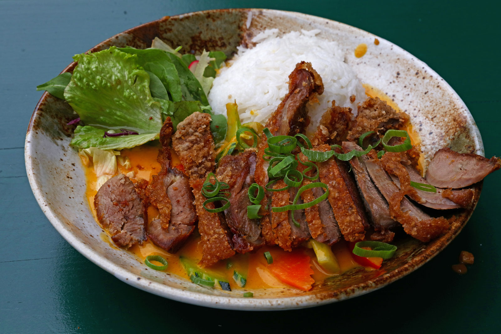 A plate filled with Caribbean curry, white rice and a side salad.