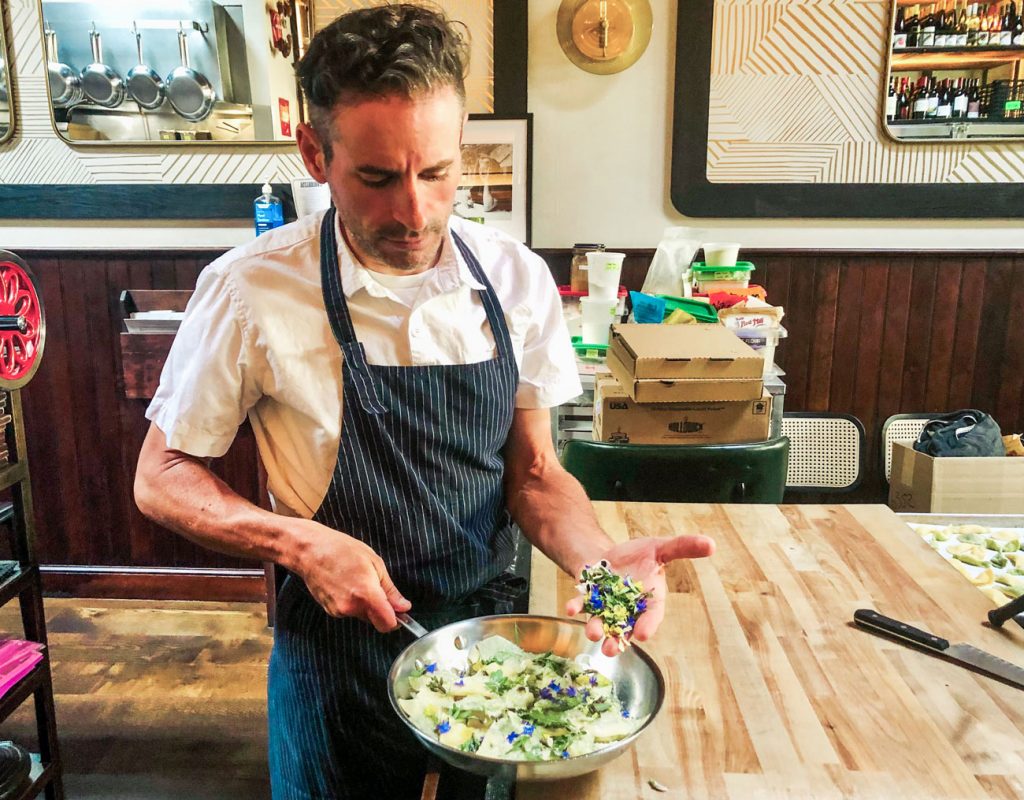 A chef working in edible flowers into a dish.