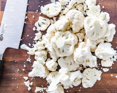 Chopped cauliflower next to a knife.