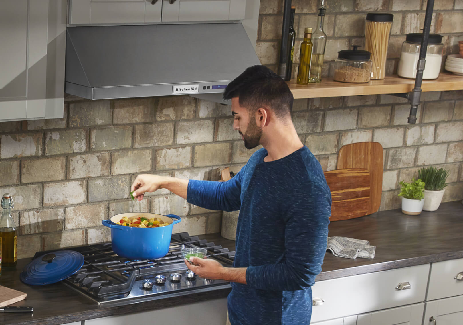 Man seasoning food with a canopy hood overhead Man seasoning food with a canopy hood overhead