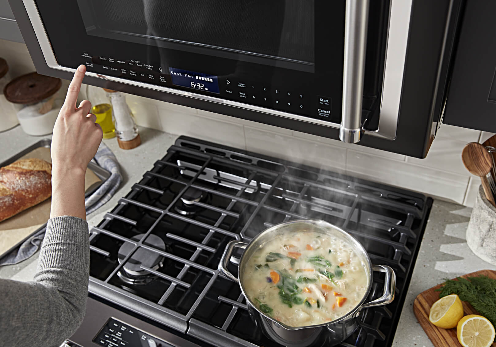 Hand selecting option on a microwave hood combination as food cooks below Hand selecting option on a microwave hood combination as food cooks below
