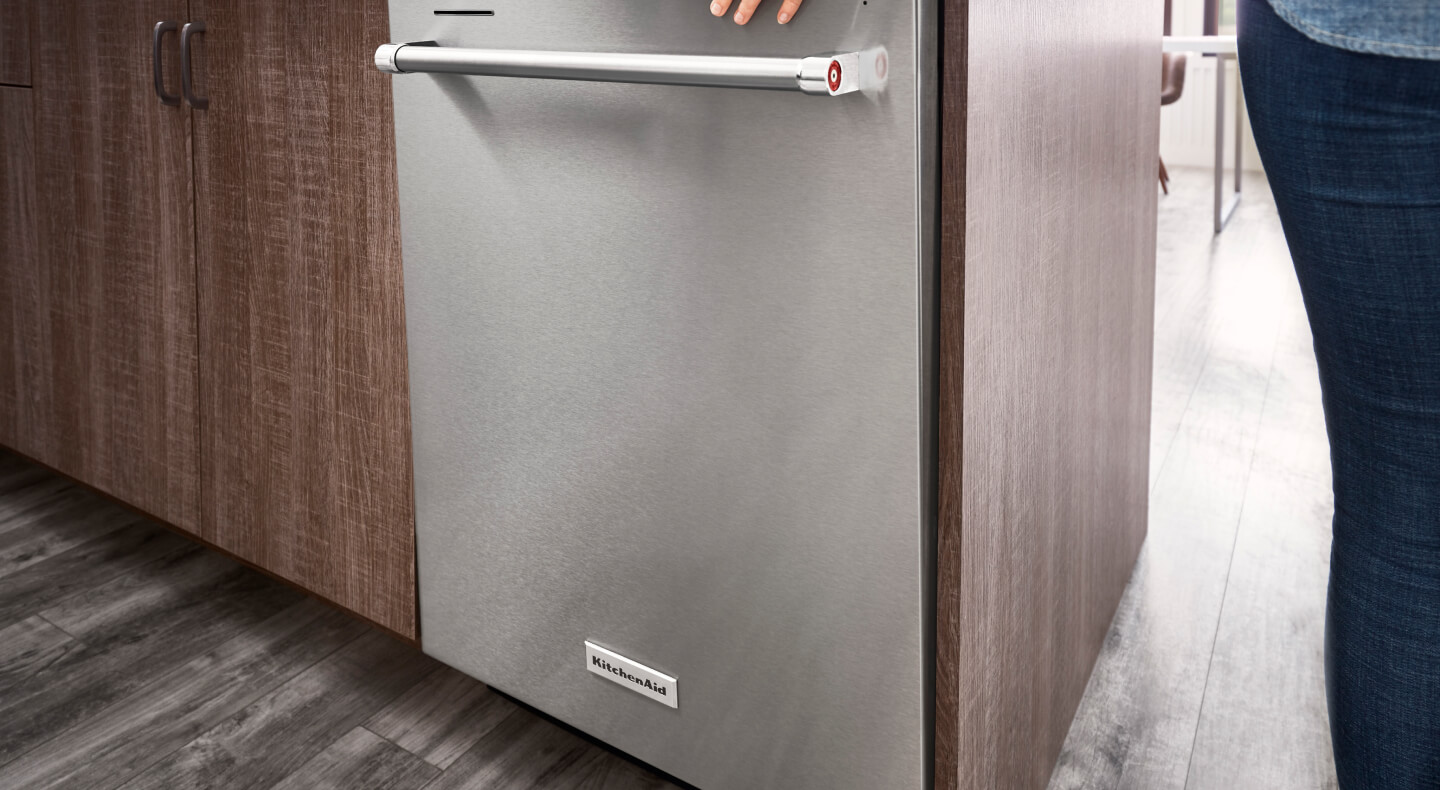 Person closing a top control dishwasher with towel bar handle