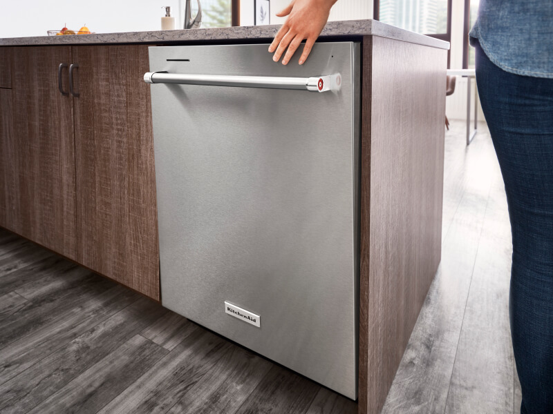 Person closing a top control dishwasher with towel bar handle