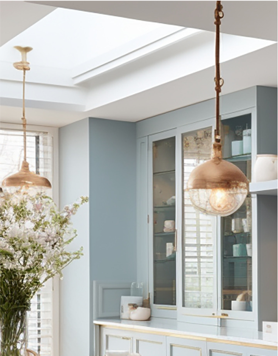 A pale blue kitchen with warm metal pendant lighting.