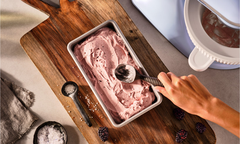 A person smoothing ice cream into a loaf pan.
