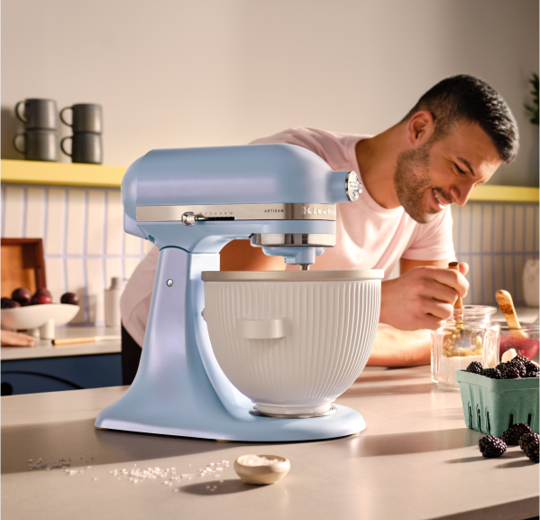 A person in the kitchen with a Blue Salt stand mixer in the foreground.