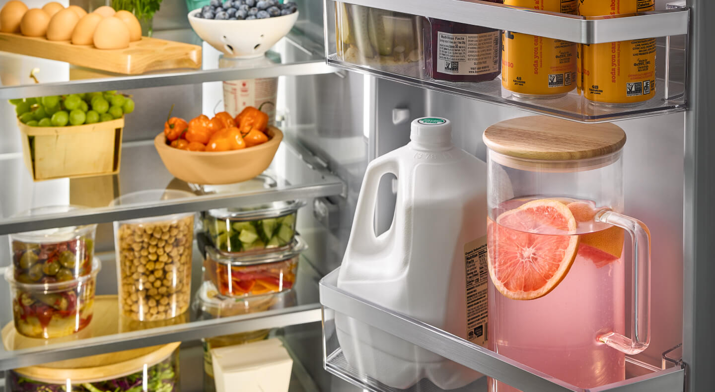 A closeup of an open refrigerator with milk and eggs in the shelves