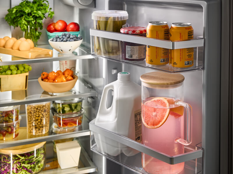 A closeup of an open refrigerator with milk and eggs in the shelves