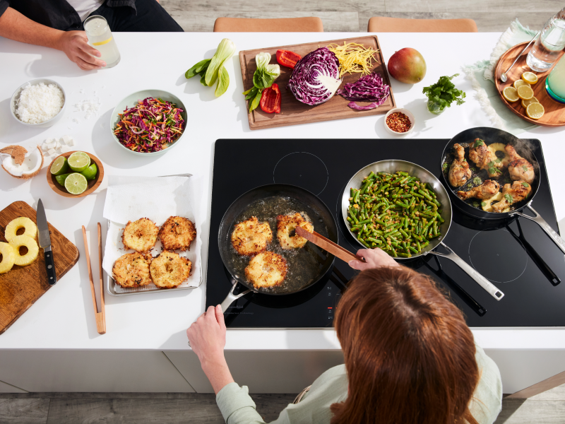 Person deep frying pineapple slices on an electric stovetop Person deep frying pineapple slices on an electric stovetop