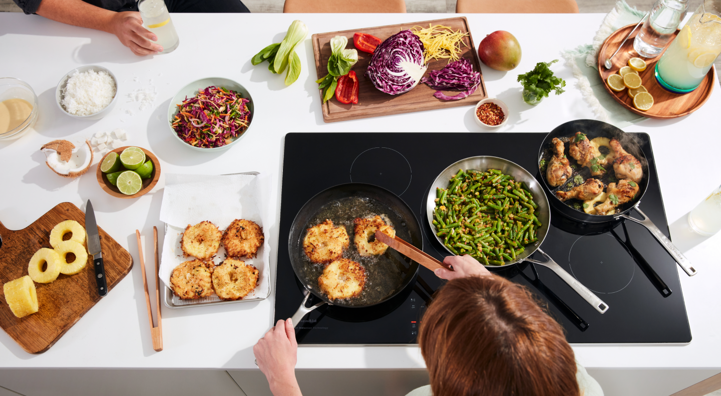 Person deep frying pineapple slices on an electric stovetop Person deep frying pineapple slices on an electric stovetop