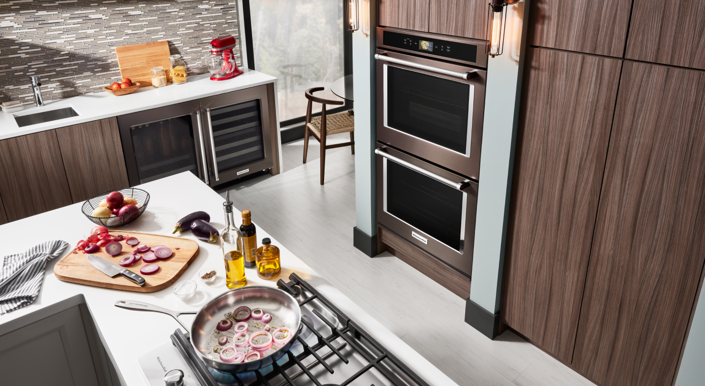 KitchenAid® double wall oven in brown cabinets across from gas stovetop KitchenAid® double wall oven in brown cabinets across from gas stovetop