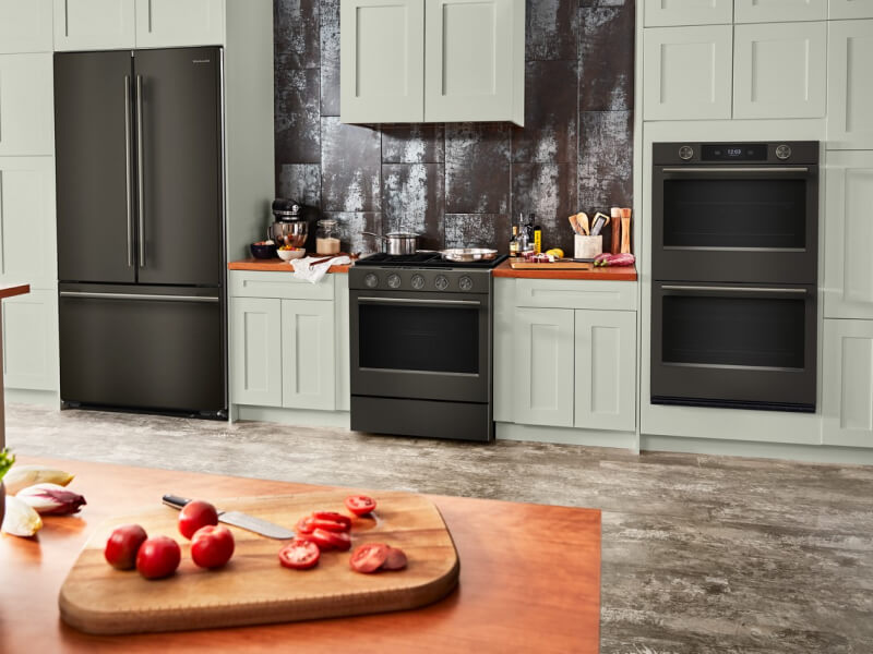 Suite of KitchenAid® Black Ore appliances in light sage green cabinetry